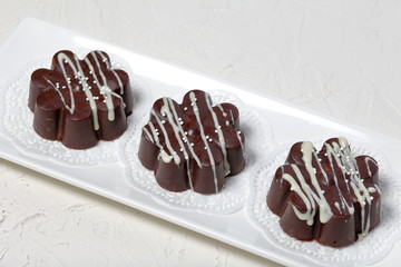 Chocolate dessert in the shape of a flower. Dark chocolate coated. Garnished with white chocolate and sprinkles.