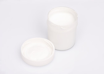 Opened white Gouache jar, on white background with copy space. Cans of different colors gouache...