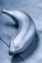Bronze colour food, silver banana on a metallic background. Trendy tropical creative concept