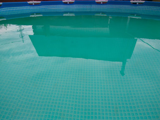 The surface of the water in the folding pool, which reflects the sky, clouds and country house