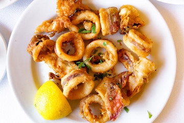 Top view of seafood meal. Fried squids with slice of lemon.