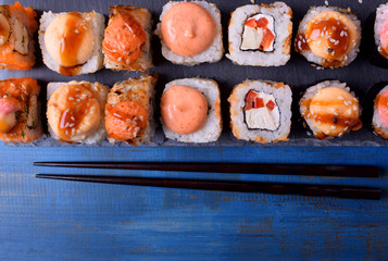 Sushi rolls assortment served on slate plate on blue table