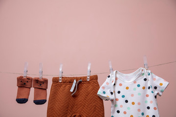 Cute baby outfit hanging from a line against a pink background