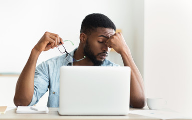 Tired african worker taking his glasses off