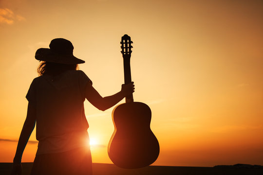 silhouette of young woman holding guitar