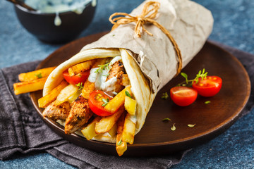 Gyros souvlaki wraps in pita bread with chicken, potatoes and tzatziki sauce. - obrazy, fototapety, plakaty