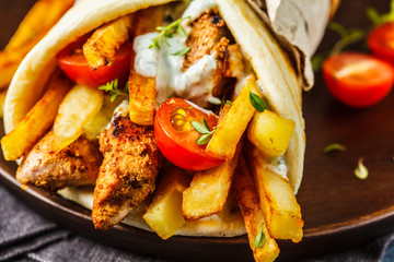 Gyros souvlaki wraps in pita bread with chicken, potatoes and tzatziki sauce.