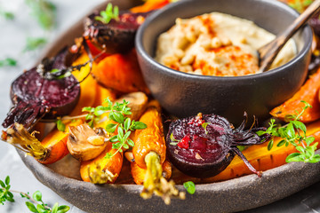 Baked vegetables with hummus in a dark dish.