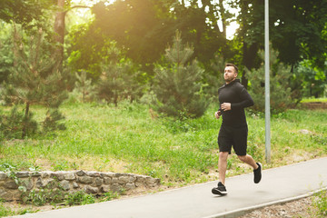 Young sporty man jogging on treadmill in park
