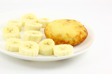 Cheesecake oval on a white plate with sliced banana pieces
