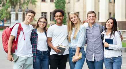 Diverse students in campus, posing in front of university