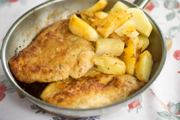 Polish breaded pork cutlet with potatoes on pan