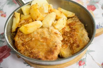 Polish breaded pork cutlet with potatoes on pan