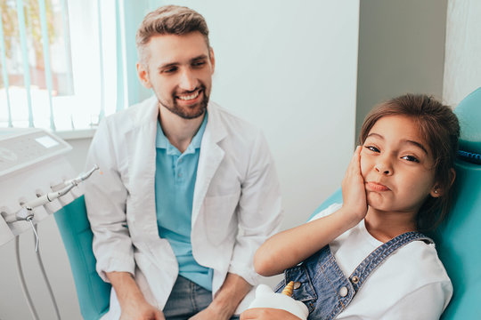 mixed race little girl showing toothache at camera. Sadness child in dental chair - Powered by Adobe