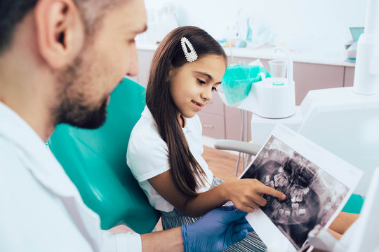Dentist and mixed race little girl looking on x-ray teeth picture.Pediatric dentistry