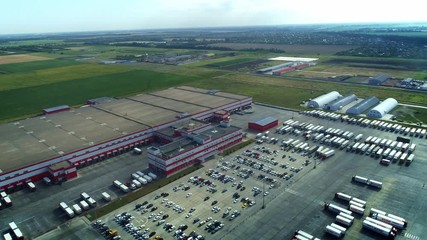 Buildings of logistics center, warehouses near the highway, view from height, a large number of trucks in the parking lot near warehouse