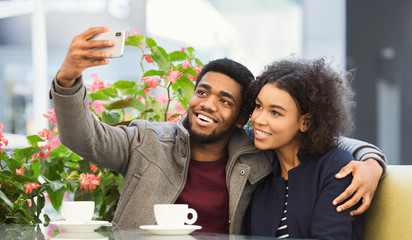African-american couple taking selfie while enjoying dating in cafe