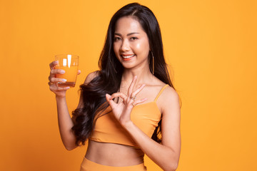 Young Asian woman show OK drink orange juice.