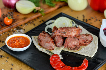 kebab on pita bread served on a black slate in a restaurant