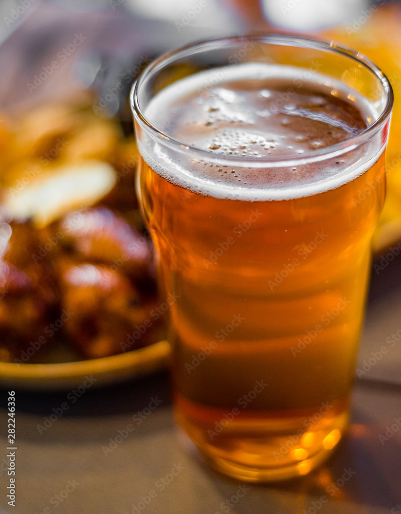 Wall mural glass of cold beer and plate with snacks on wooden table background on bar or pub