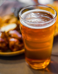 glass of cold beer and plate with snacks on wooden table background on bar or pub