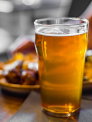 glass of cold beer and plate with snacks on wooden table background on bar or pub