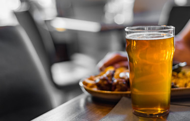 glass of cold beer and plate with snacks on wooden table background on bar or pub