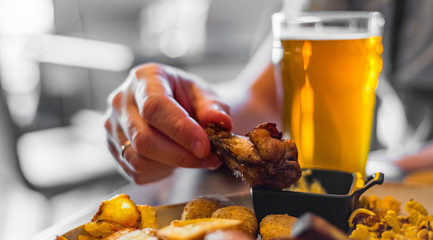 man hand with glass of cold beer and plate with snacks on wooden table background on bar or pub