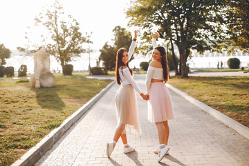 Fototapeta premium Beautiful girls in a park. Friends have fun in a summer city