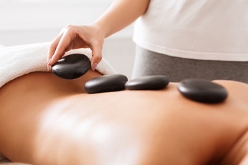 Obraz na płótnie Canvas Masseuse doing hot stones massage to female client