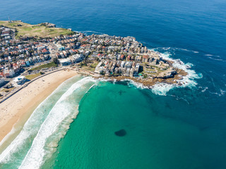 Beautiful aerial high angle drone view of the suburbs of Bondi Beach and North Bondi, one of the most famous beaches in Sydney, New South Wales, Australia. Large shoal of fish visible in the ocean.