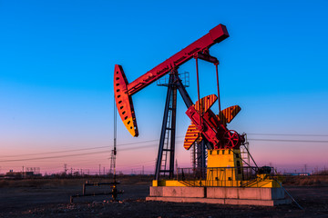 Oil pumps are running at different angles at sunset in oil field.