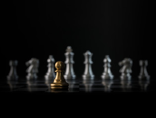 Golden chess pawn is facing the silver opponent chess on black background. Leader, leadership, business strategy, challenge, brave or fearless concept.