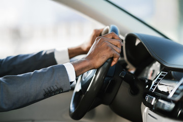Businessman driving car on highway, holding hands on wheel