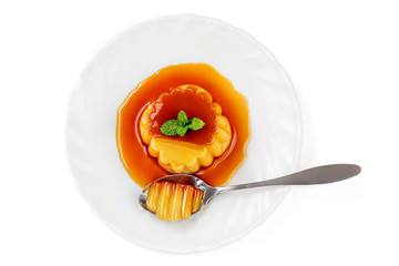Flan or  caramel custard pudding with spoon and mint on white plate isolated  white background....