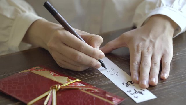 ご祝儀袋に記名する女性の手元