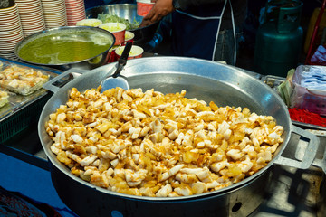 Street food. fried noodles in a wok with chicken on the open fire
