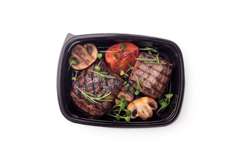 Grill cooked meat steaks with vegetables in delivery box