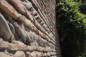 Fototapeta na wymiar Antique stone wall made of large smooth stones and tree branches