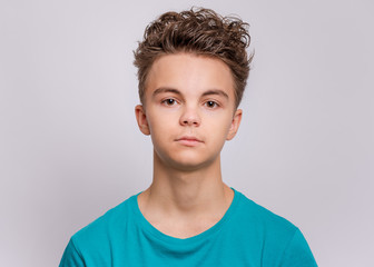 Portrait of teen boy in blue t-shirt in studio. Photo of adorable young happy boy looking at camera on white background.