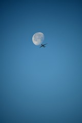 Aeroplane and the moon in a blue sky background
