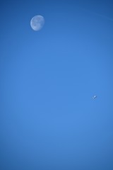 Aeroplane and the moon in a blue sky background