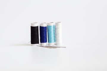  Threads of different colors with the coils in a row and swing needle on white background