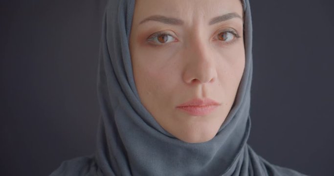 Closeup portrait of young attractive muslim woman in hijab looking at camera with background isolated on gray