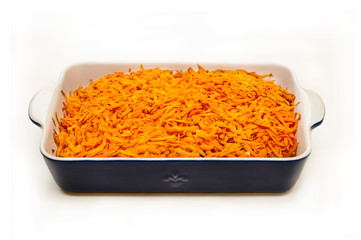 Sliced carrots lie on a baking sheet in the kitchen on a white table.