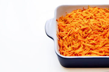 Sliced carrots lie on a baking sheet in the kitchen on a white table.