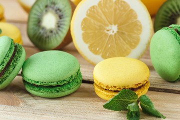 Green and yellow french macarons with kiwi, lemon and mint decorations
