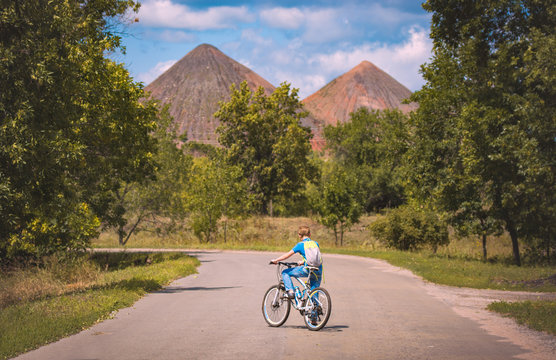 Boy on a bike on a road against slagheap