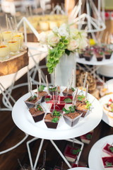 Tasty sweets on a brown rustic wooden banquet table. Summer wedding in the forest. Banquet table. Wedding candy bar. - 282257718