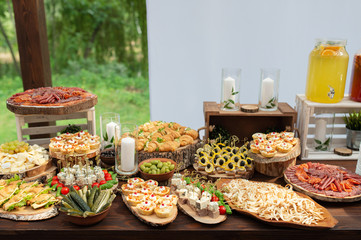 Tasty meals on a brown rustic wooden banquet table. Summer wedding in the forest - 282257764